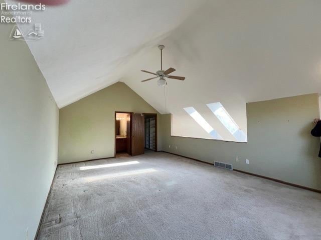 bonus room with ceiling fan, vaulted ceiling with skylight, and light colored carpet