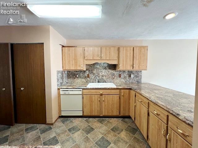 kitchen with white dishwasher, decorative backsplash, light stone countertops, and sink