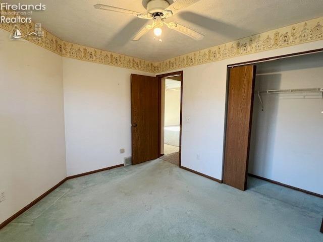 unfurnished bedroom with ceiling fan, a closet, and light colored carpet