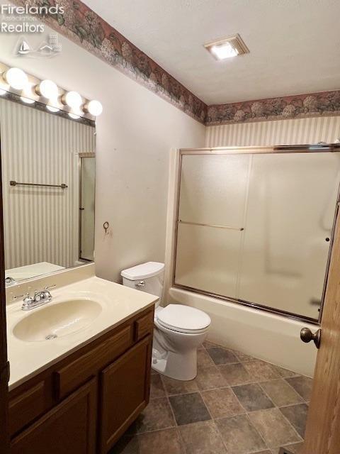 full bathroom featuring shower / bath combination with glass door, vanity, and toilet