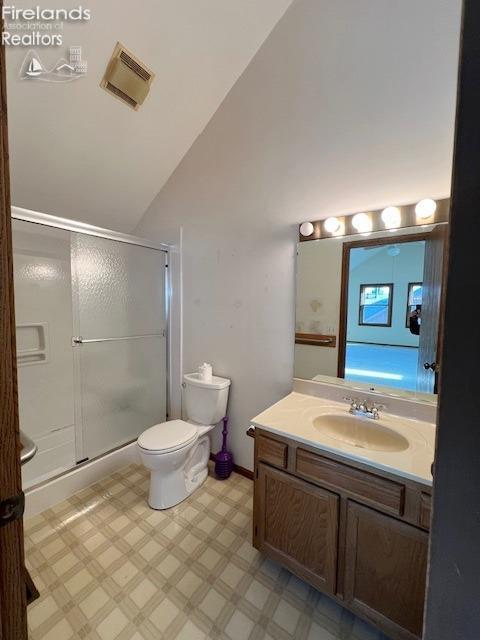 bathroom featuring vanity, a shower with shower door, lofted ceiling, and toilet