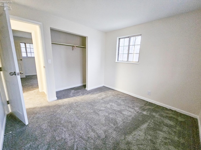 unfurnished bedroom featuring dark carpet and a closet