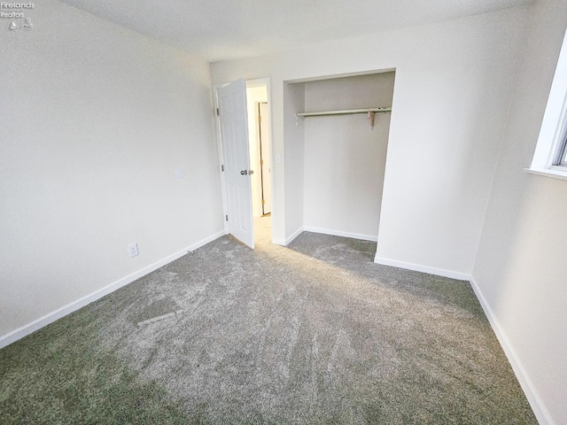 unfurnished bedroom featuring dark carpet and a closet