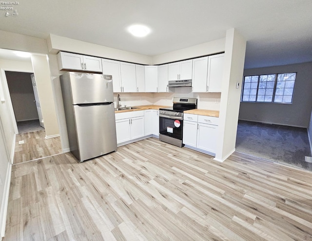 kitchen with wooden counters, appliances with stainless steel finishes, light wood-type flooring, sink, and white cabinets