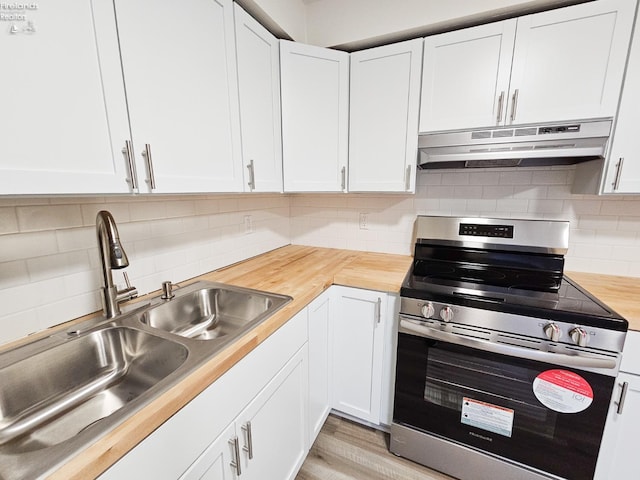 kitchen featuring white cabinets, wood counters, sink, and stainless steel stove