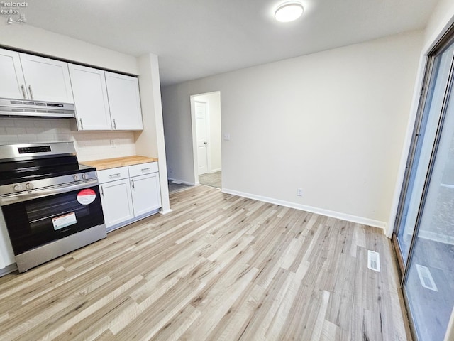 kitchen featuring light wood-type flooring, tasteful backsplash, stainless steel range oven, white cabinetry, and butcher block counters