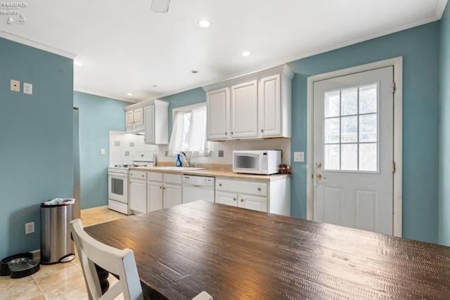 kitchen with backsplash, ornamental molding, white appliances, sink, and white cabinets