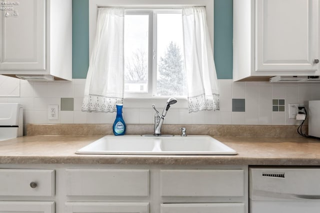 kitchen with dishwasher, tasteful backsplash, white cabinetry, and sink