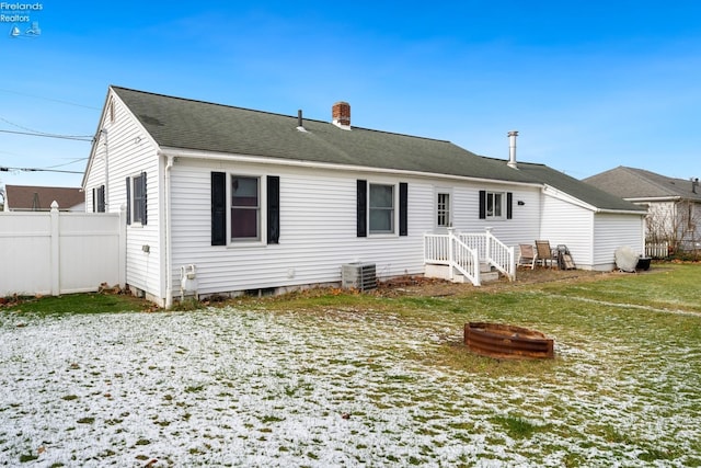 rear view of house with a fire pit, cooling unit, and a lawn