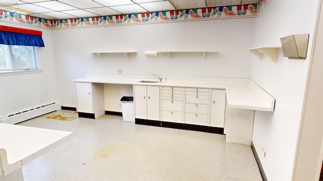 unfurnished office featuring sink, a baseboard radiator, and a drop ceiling