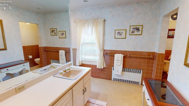 bathroom featuring vanity, toilet, radiator, and tile walls