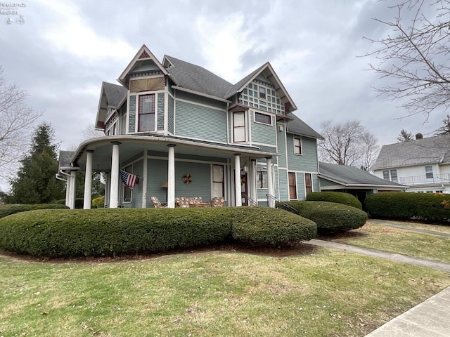 victorian house featuring a porch and a front lawn