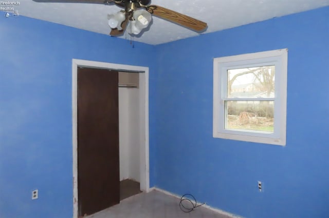 unfurnished bedroom with ceiling fan and a closet