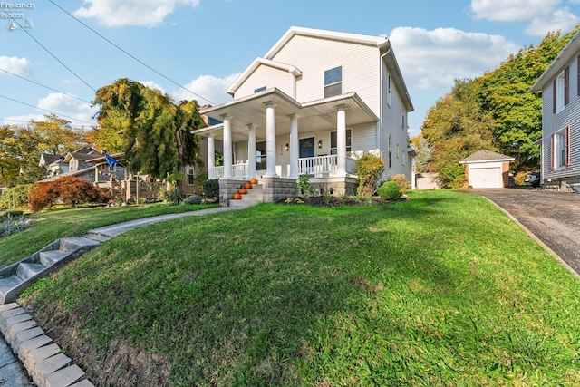 view of front facade with covered porch, a garage, an outbuilding, and a front yard