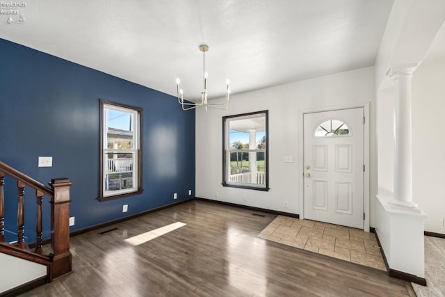 entryway with dark hardwood / wood-style flooring, decorative columns, and a notable chandelier