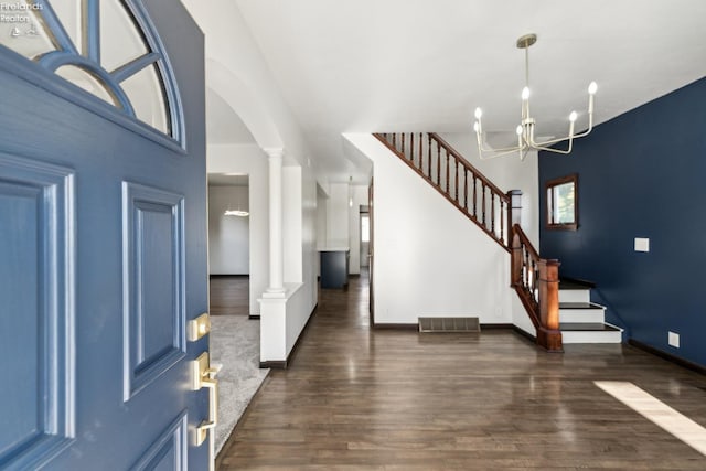 entrance foyer featuring a notable chandelier, dark hardwood / wood-style flooring, and ornate columns