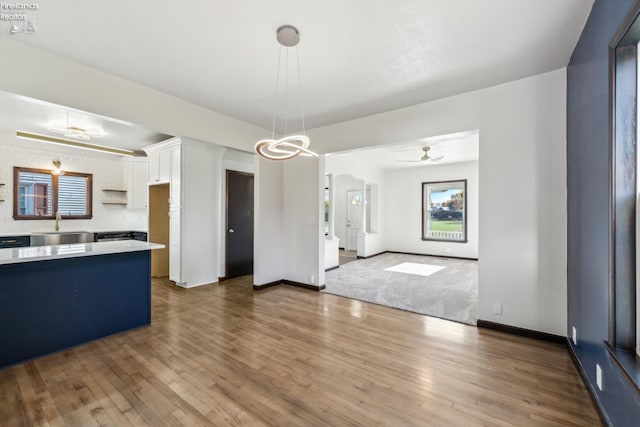 kitchen with white cabinetry, sink, ceiling fan, hanging light fixtures, and dark hardwood / wood-style flooring