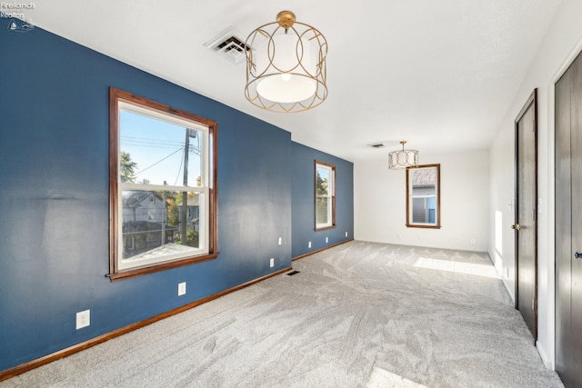 carpeted empty room featuring a chandelier