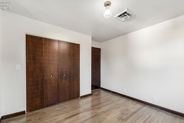 unfurnished bedroom with light hardwood / wood-style flooring and a closet