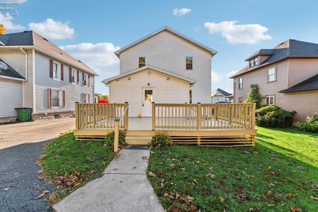 rear view of house featuring a lawn and a wooden deck