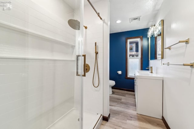 bathroom featuring vanity, toilet, wood-type flooring, and walk in shower