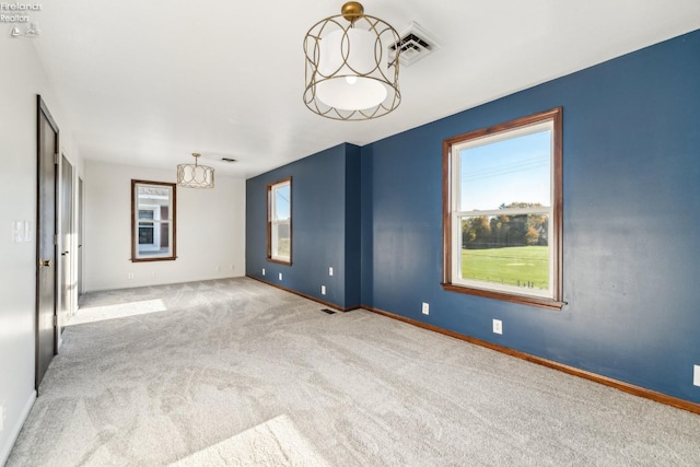 carpeted spare room with a notable chandelier