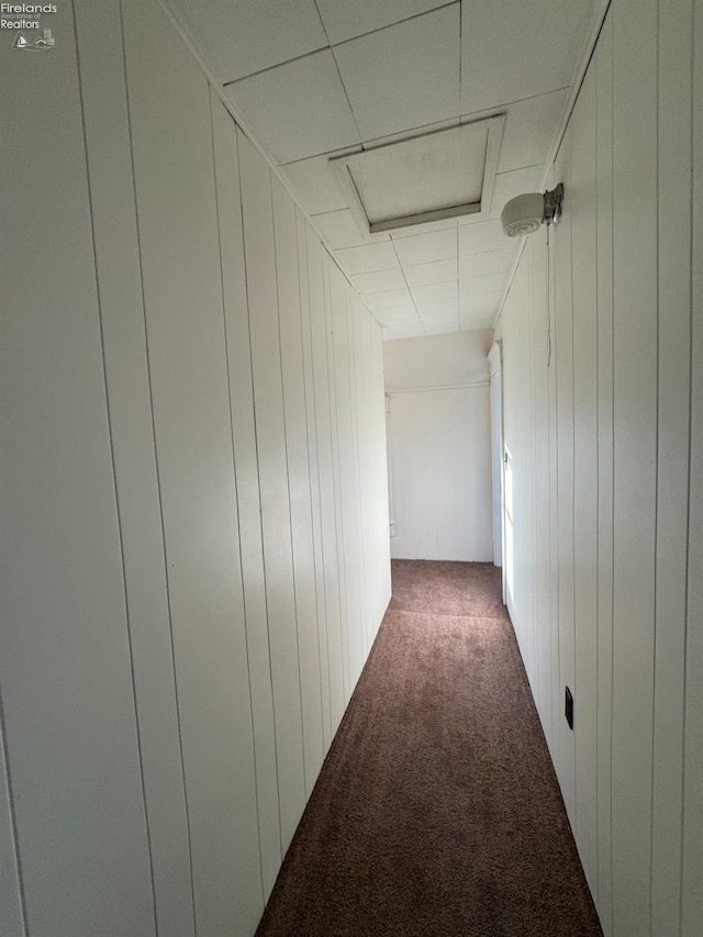 hall featuring wooden walls and dark carpet