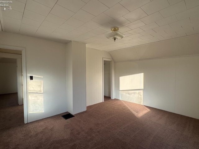 unfurnished room featuring dark colored carpet and vaulted ceiling