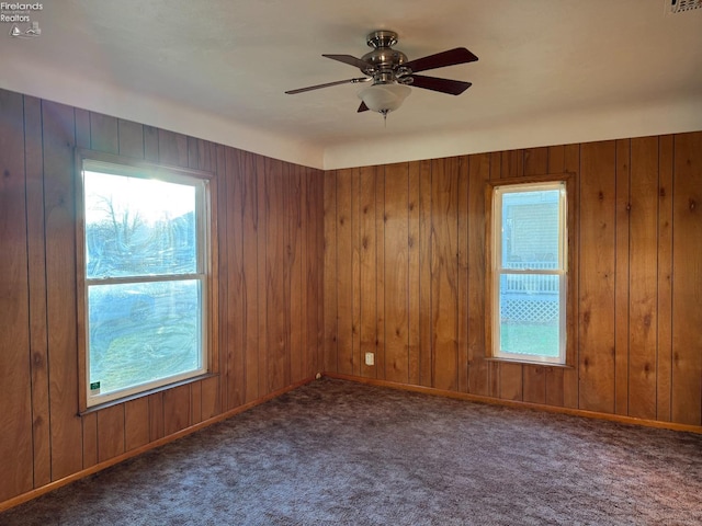 carpeted spare room featuring ceiling fan and wooden walls