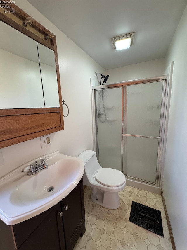 bathroom with vanity, a shower with shower door, and toilet