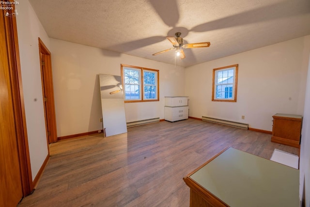 unfurnished bedroom with multiple windows, ceiling fan, and a baseboard heating unit