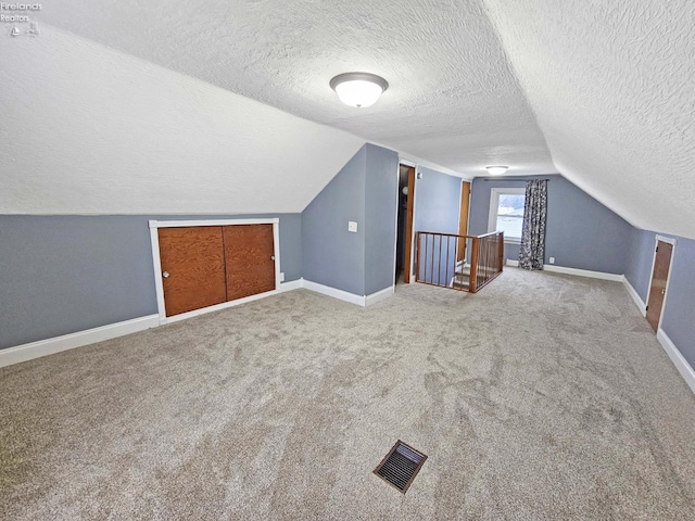 additional living space featuring carpet flooring, a textured ceiling, and vaulted ceiling