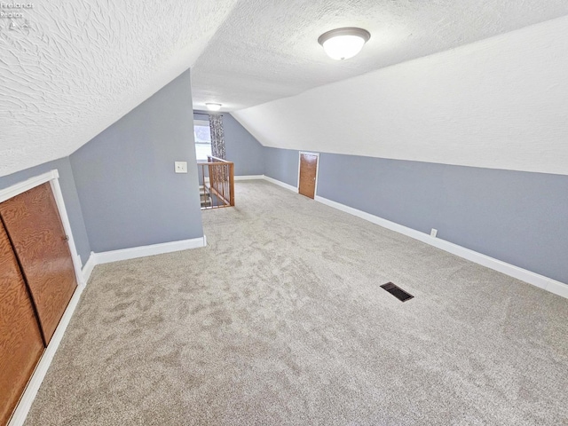 bonus room featuring vaulted ceiling, carpet floors, and a textured ceiling