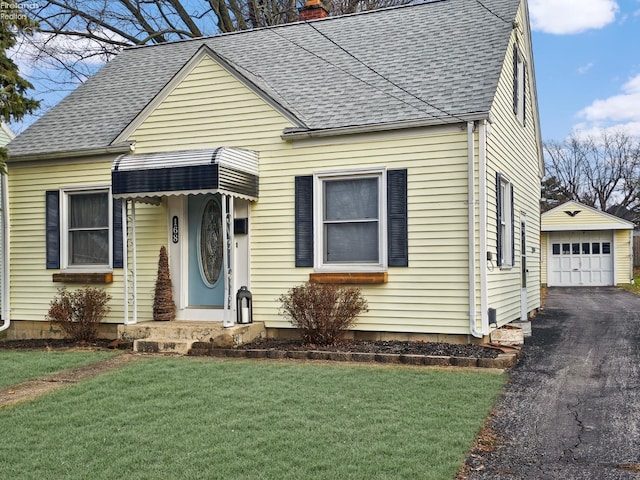 view of front of home featuring a front yard, a garage, and an outdoor structure