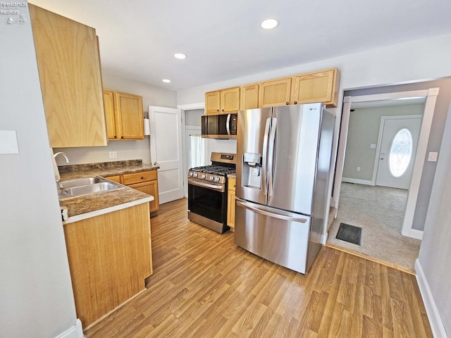 kitchen featuring light brown cabinetry, light wood-type flooring, stainless steel appliances, and sink