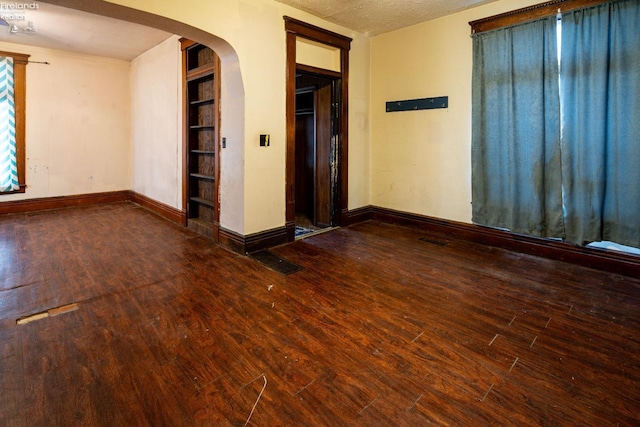 spare room with a textured ceiling and dark hardwood / wood-style floors