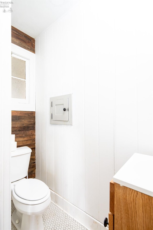 bathroom with wood walls, tile patterned flooring, vanity, and toilet