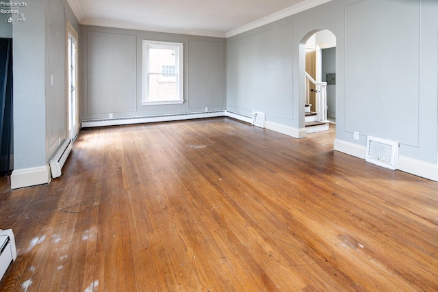 empty room with hardwood / wood-style flooring, ornamental molding, and a baseboard heating unit