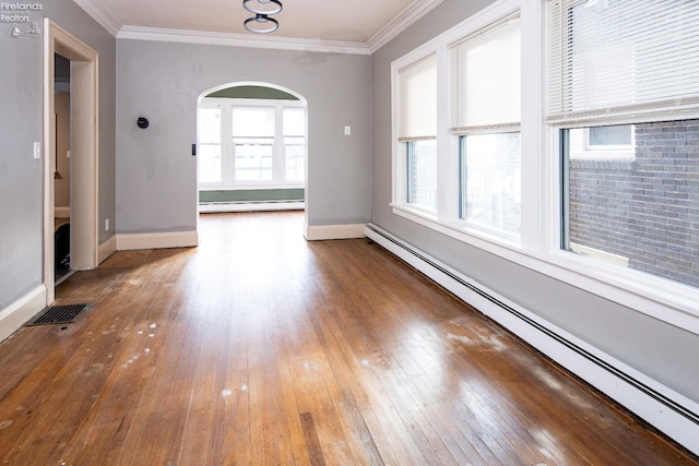 empty room featuring hardwood / wood-style flooring, ornamental molding, and a baseboard heating unit