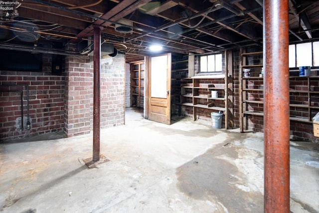 basement featuring plenty of natural light and brick wall