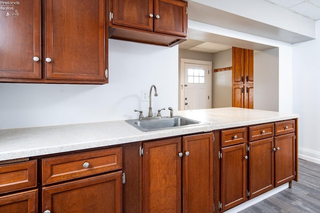 kitchen featuring kitchen peninsula, sink, and dark wood-type flooring