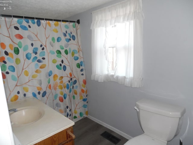 bathroom featuring vanity, a textured ceiling, hardwood / wood-style flooring, and toilet