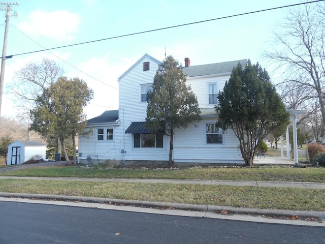 view of front of property with a front yard and a storage shed