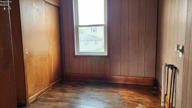 empty room featuring wooden walls and dark wood-type flooring