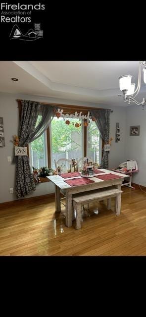 dining space with hardwood / wood-style flooring and an inviting chandelier