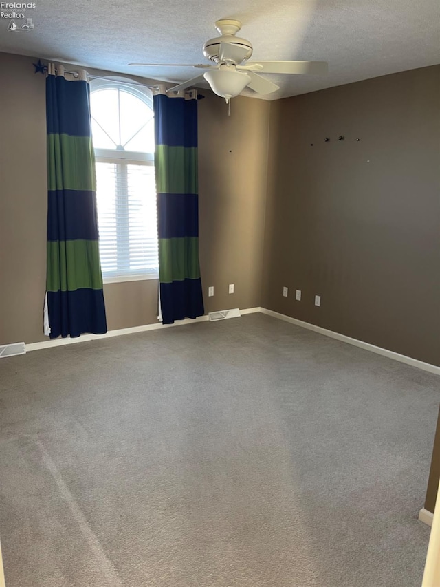 carpeted empty room with ceiling fan and a textured ceiling