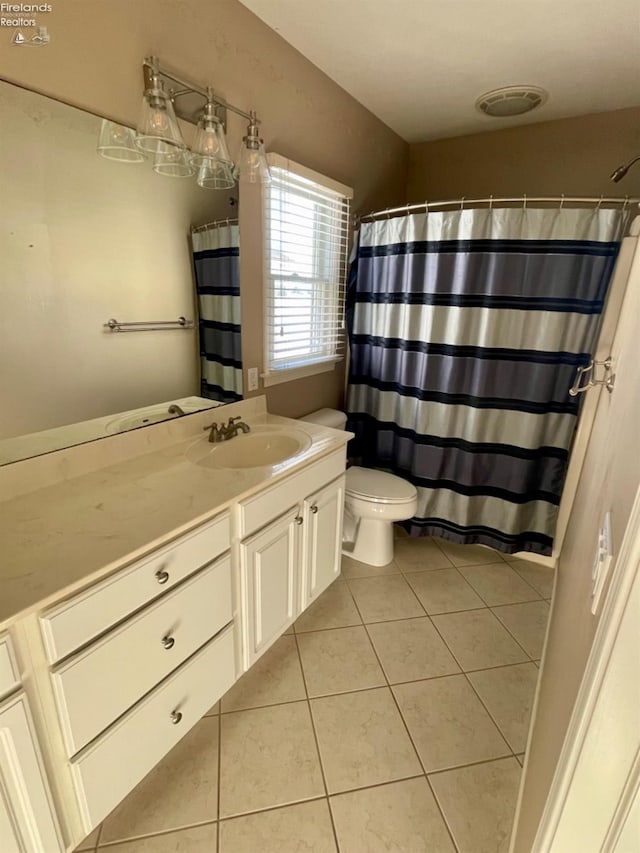 bathroom with toilet, vanity, and tile patterned floors