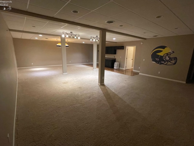 basement featuring a paneled ceiling and carpet