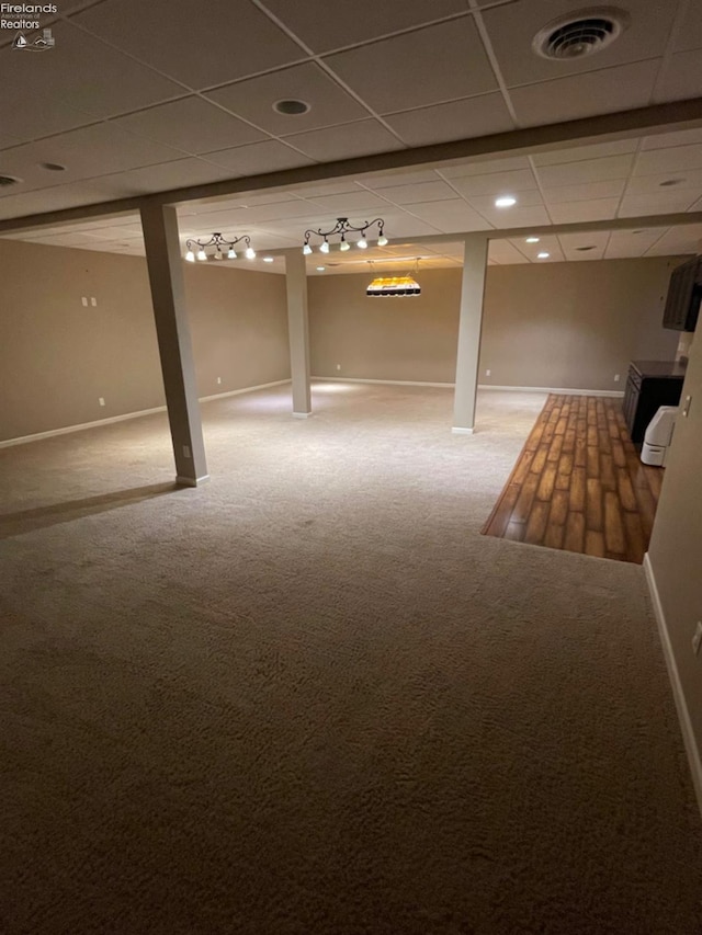 basement featuring a drop ceiling and carpet floors