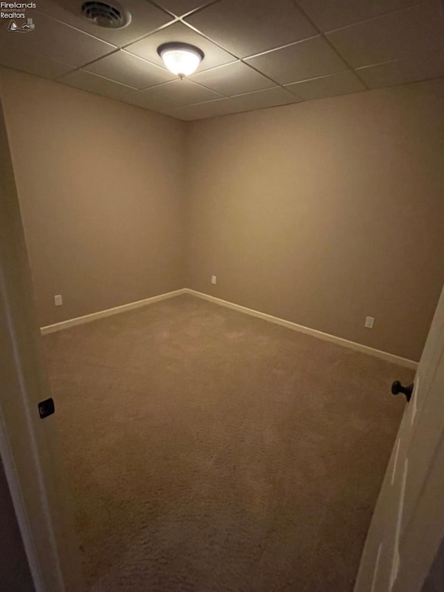 carpeted spare room featuring a drop ceiling